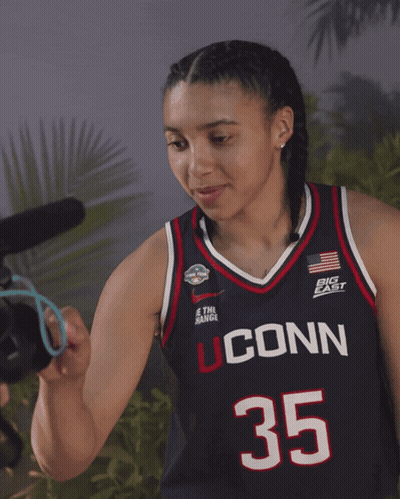 A Woman Wearing A Jersey That Says Uconn 35 On It GIF