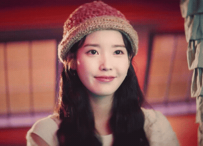 A Woman Wearing A Knitted Hat Looks At The Camera And Smiles GIF