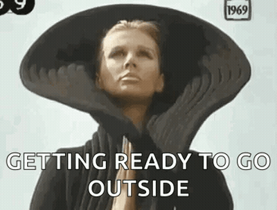 A Woman Wearing A Large Hat And Gloves Is Getting Ready To Go Outside . GIF