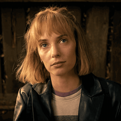 A Woman Wearing A Leather Jacket And A Striped Shirt Looks At The Camera GIF