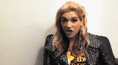 A Woman Wearing A Leather Jacket With Studs And A Shirt That Says The World GIF