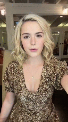 A Woman Wearing A Leopard Print Dress Is Standing In Front Of A Mirror GIF