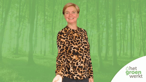 A Woman Wearing A Leopard Print Shirt Is Standing In Front Of A Green Forest GIF
