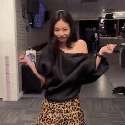 A Woman Wearing A Leopard Print Skirt And A Black Top Is Dancing In A Room . GIF