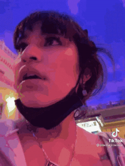 A Woman Wearing A Mask And A Necklace Is Looking Up At Something . GIF