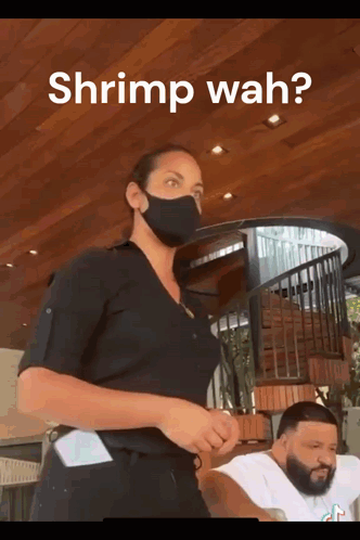 A Woman Wearing A Mask Asks A Man If He Wants Shrimp Wah GIF