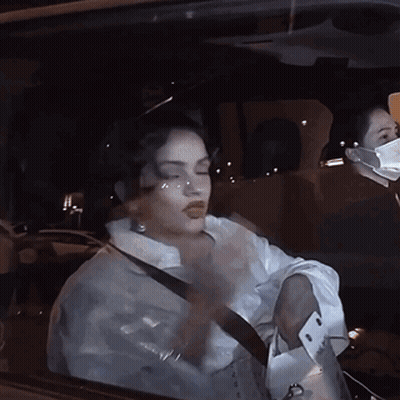 A Woman Wearing A Mask Is Driving A Car GIF