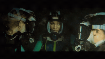 A Woman Wearing A Mask With The Letter D On It Looks At Another Woman GIF