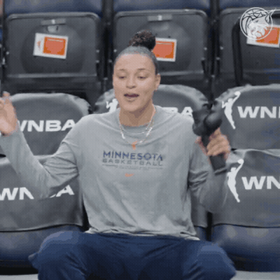 A Woman Wearing A Minnesota Basketball Shirt Is Sitting In A Stadium GIF