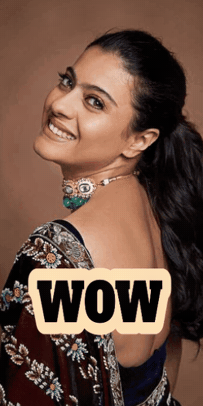 A Woman Wearing A Necklace And A Blue Blouse Is Smiling With The Word Wow Behind Her GIF