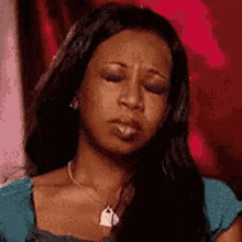 A Woman Wearing A Necklace And Earrings Is Making A Funny Face With Her Eyes Closed . GIF