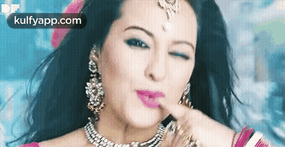 A Woman Wearing A Necklace And Earrings Is Making A Funny Face With Her Finger On Her Lips . GIF