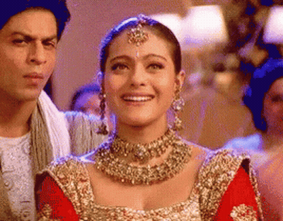 A Woman Wearing A Necklace And Earrings Is Smiling While Standing Next To A Man . GIF
