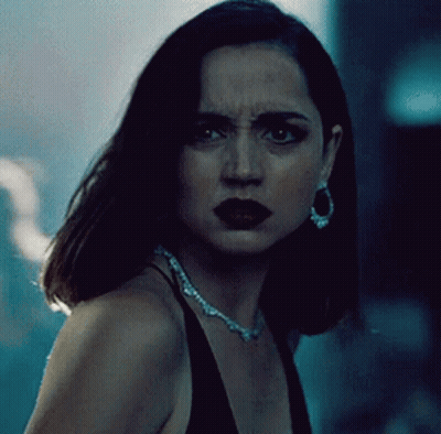 A Woman Wearing A Necklace And Earrings Looks At The Camera With A Serious Look On Her Face GIF