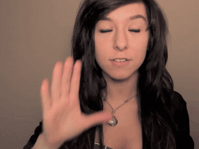 A Woman Wearing A Necklace Holds Her Hand Up To Her Face GIF