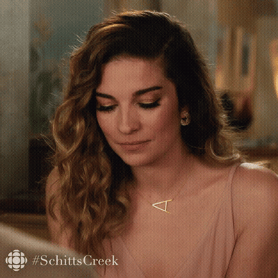 A Woman Wearing A Necklace With A Letter T On It GIF