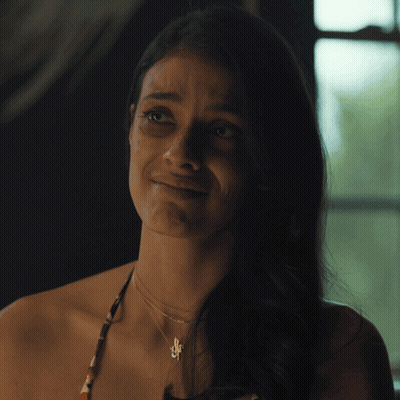 A Woman Wearing A Necklace With A Pendant That Says S On It GIF