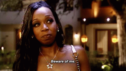 A Woman Wearing A Necklace With A Star On It Says " Beware Of Me " GIF