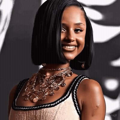 A Woman Wearing A Necklace With Coins On It Smiles For The Camera GIF