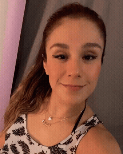 A Woman Wearing A Necklace With The Name Amy On It Smiles For The Camera GIF
