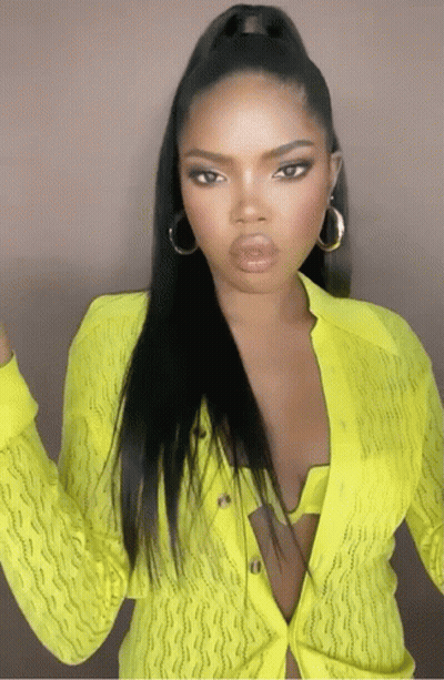 A Woman Wearing A Neon Yellow Cardigan And Earrings GIF