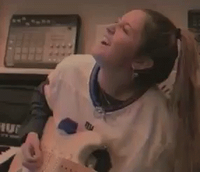 A Woman Wearing A New York Giants Jersey Is Playing A Guitar GIF