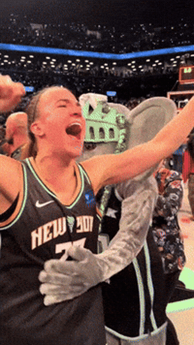 A Woman Wearing A New York Jersey Celebrates With A Mascot GIF