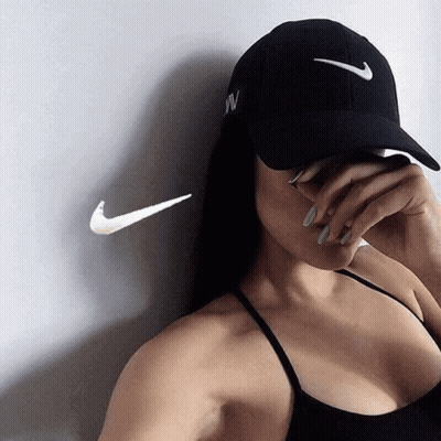 A Woman Wearing A Nike Hat Covering Her Face With Her Hand GIF