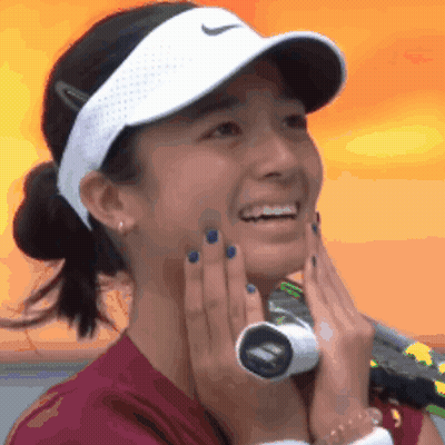 A Woman Wearing A Nike Hat Is Smiling And Holding A Tennis Racket GIF