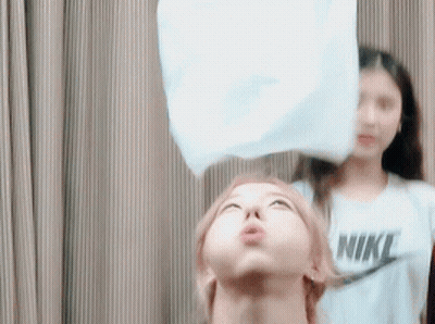 A Woman Wearing A Nike Shirt Is Blowing Up A White Balloon GIF