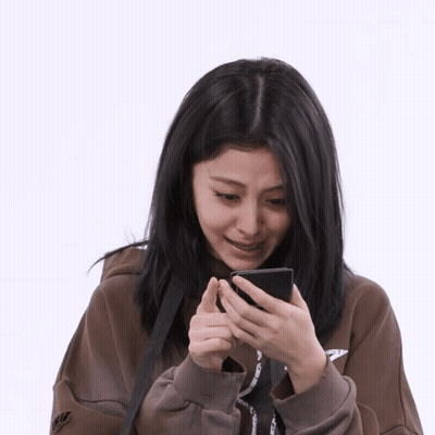 A Woman Wearing A Nike Sweatshirt Looks At Her Cell Phone GIF