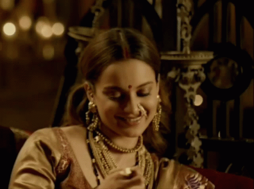 A Woman Wearing A Nose Ring And A Necklace Smiles GIF