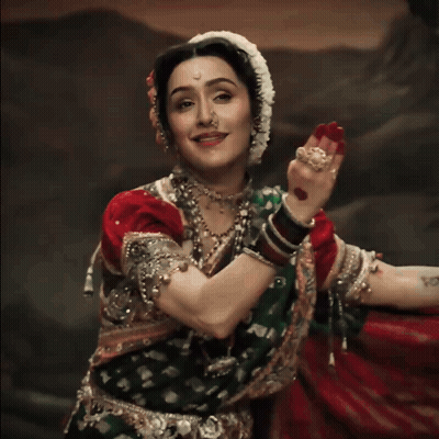 A Woman Wearing A Nose Ring And A Red And Green Dress GIF