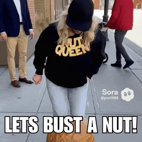 A Woman Wearing A Nut Queen Sweatshirt Is Holding A Nut GIF