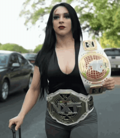 A Woman Wearing A Nxt Belt Is Walking Down A Street GIF
