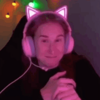 A Woman Wearing A Pair Of Pink Cat Ears Headphones Is Sitting In A Chair . GIF