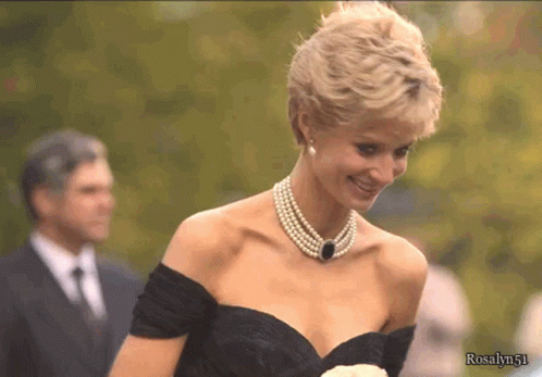 A Woman Wearing A Pearl Necklace And A Black Dress With The Name Rosalyn51 On The Bottom GIF