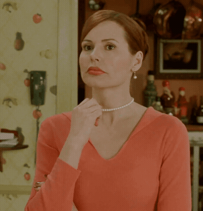 A Woman Wearing A Pearl Necklace And A Red Shirt GIF