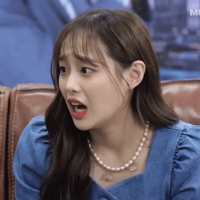 A Woman Wearing A Pearl Necklace Is Sitting On A Couch With Her Mouth Open GIF