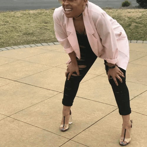 A Woman Wearing A Pink Blazer And Black Jeans Is Kneeling Down GIF