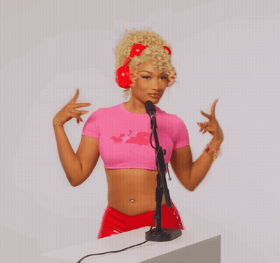 A Woman Wearing A Pink Crop Top And Red Headphones Is Standing In Front Of A Microphone GIF