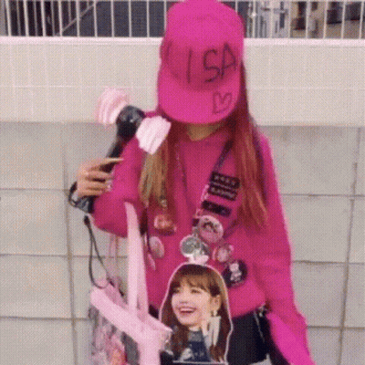 A Woman Wearing A Pink Hat And A Pink Sweater Is Holding A Microphone And A Backpack . GIF