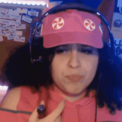 A Woman Wearing A Pink Hat And Headphones Is Holding Something GIF