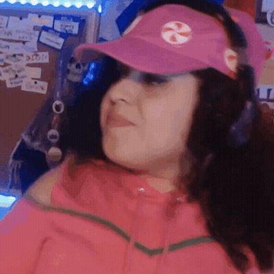 A Woman Wearing A Pink Hat And Headphones Is Making A Funny Face . GIF