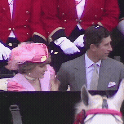 A Woman Wearing A Pink Hat Is Sitting Next To A Man In A Suit GIF
