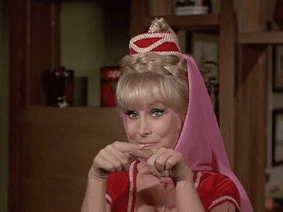 A Woman Wearing A Pink Head Scarf And A Red Top Is Making A Funny Face . GIF