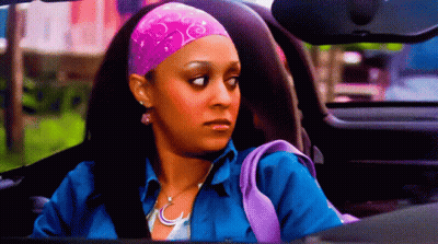 A Woman Wearing A Pink Headband And A Blue Shirt Is Driving A Car GIF