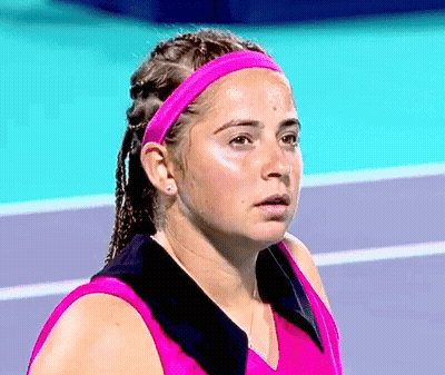 A Woman Wearing A Pink Headband And Earrings Looks At The Camera GIF