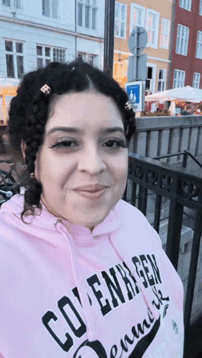 A Woman Wearing A Pink Hoodie That Says Copenhagen On It GIF