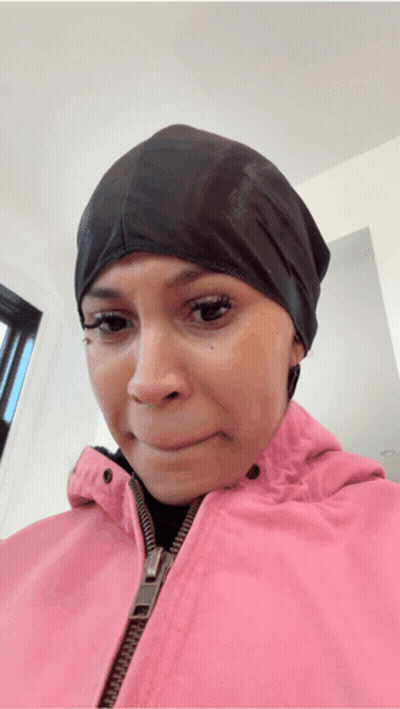 A Woman Wearing A Pink Jacket And A Black Hat Is Making A Sad Face GIF